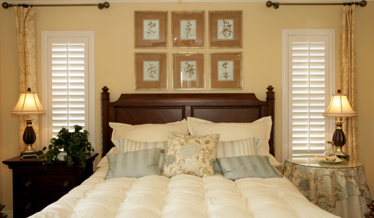Beige bedroom with white plantation shutters covering windows in New Brunswick 